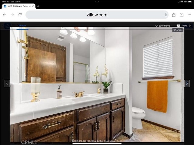 bathroom with toilet, vanity, and tile patterned floors