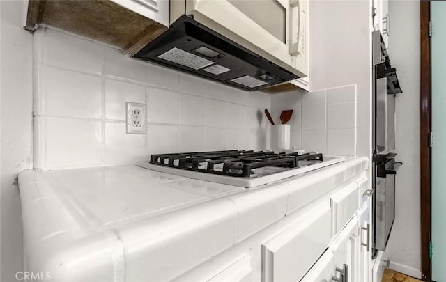 kitchen with range hood, white cabinets, decorative backsplash, and gas cooktop