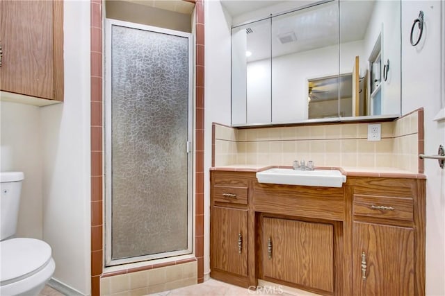 bathroom with tasteful backsplash, vanity, a shower with door, and toilet