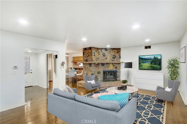 living room featuring a brick fireplace and hardwood / wood-style flooring