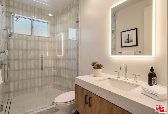 bathroom featuring toilet, vanity, and a shower with shower door