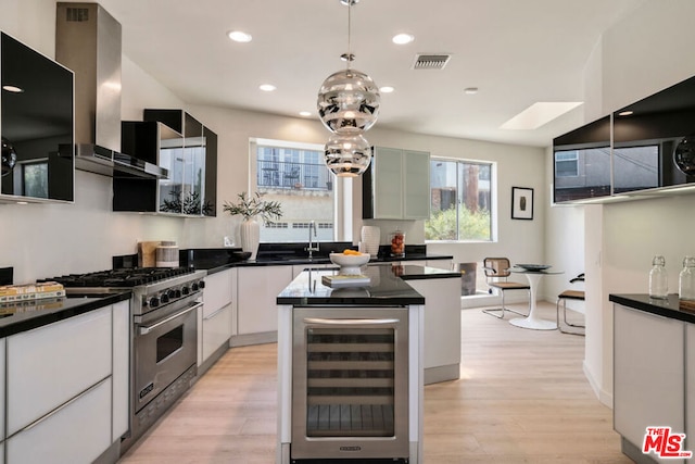 kitchen featuring premium stove, range hood, a center island, beverage cooler, and white cabinetry