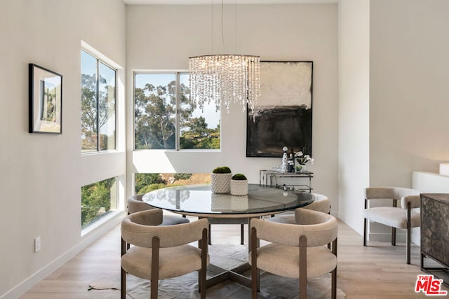 dining area with light hardwood / wood-style flooring, an inviting chandelier, and a wealth of natural light