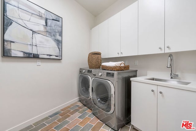 washroom with washing machine and dryer, cabinets, and sink