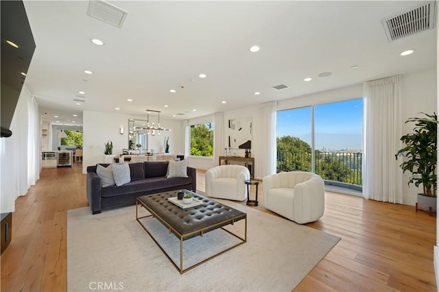 living room with light wood-type flooring and an inviting chandelier