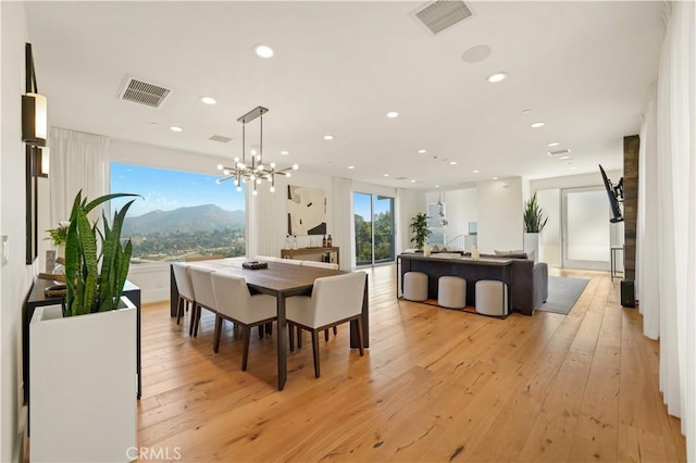 dining room featuring light wood-type flooring, a notable chandelier, and a mountain view