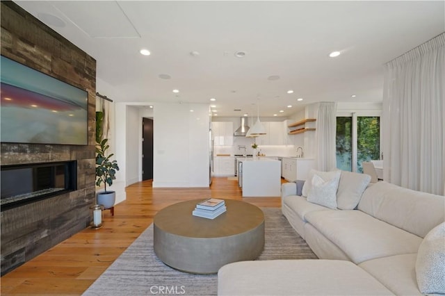 living room featuring sink, a large fireplace, and light hardwood / wood-style floors