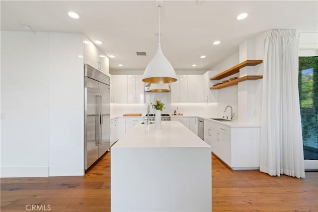 kitchen featuring light hardwood / wood-style floors, stainless steel built in refrigerator, pendant lighting, white cabinets, and sink