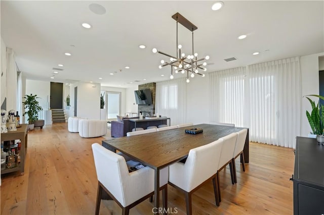 dining space with light hardwood / wood-style floors and a notable chandelier