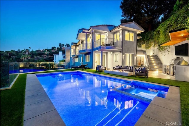 pool at dusk featuring an outdoor kitchen, an in ground hot tub, a patio, a grill, and an outdoor living space