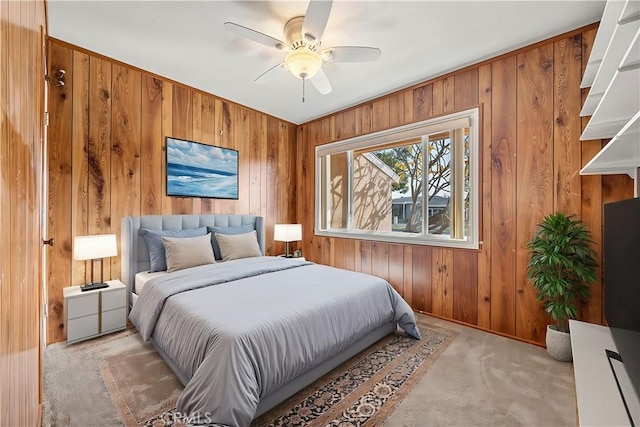 bedroom with light carpet, ceiling fan, and wood walls