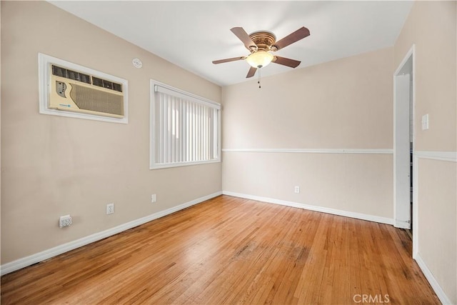 spare room featuring ceiling fan, light hardwood / wood-style flooring, and a wall mounted air conditioner