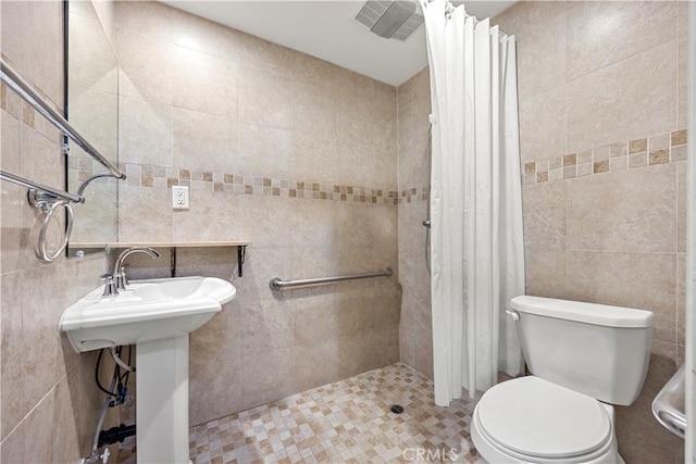 bathroom with toilet, tile walls, walk in shower, and sink