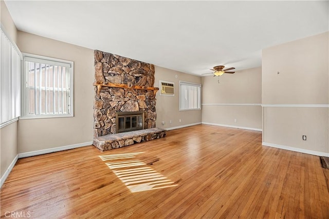 unfurnished living room with a fireplace, light wood-type flooring, ceiling fan, and a wall mounted AC