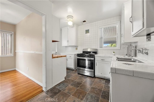 kitchen featuring sink, white cabinets, tasteful backsplash, and stainless steel gas range