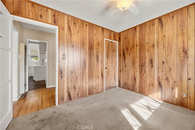 spare room with wood walls, ceiling fan, and carpet