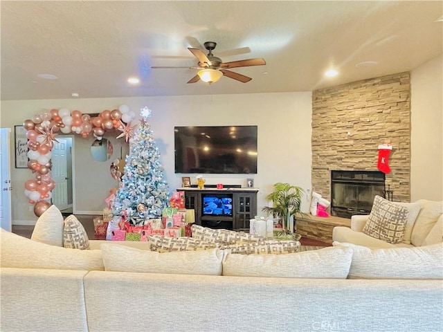 living room with ceiling fan and a stone fireplace