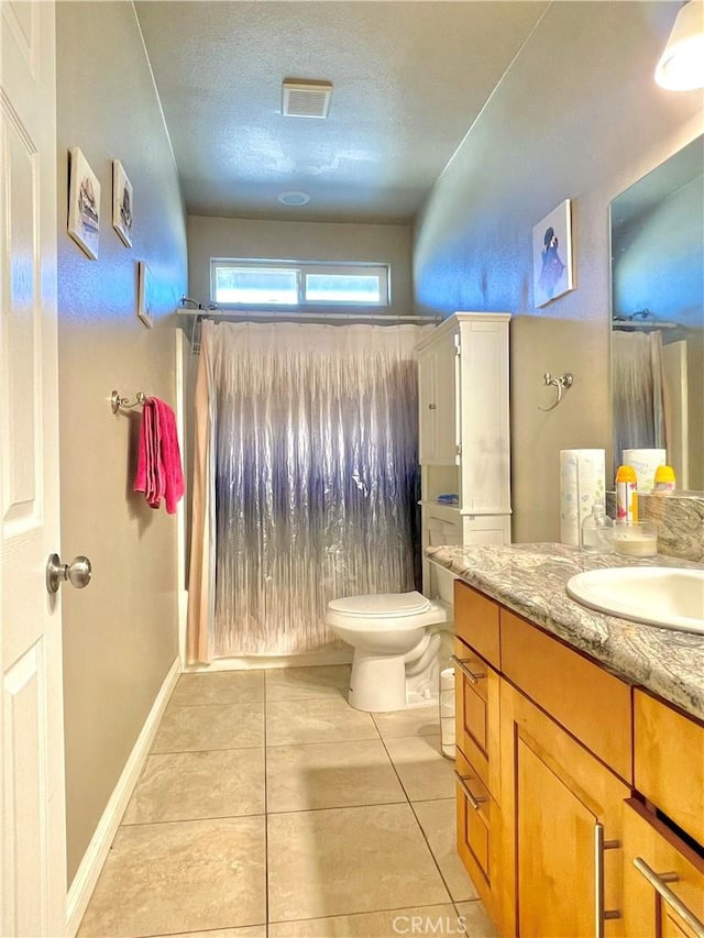 bathroom featuring toilet, vanity, tile patterned flooring, and a textured ceiling