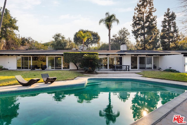 back of property featuring a patio area and a lawn