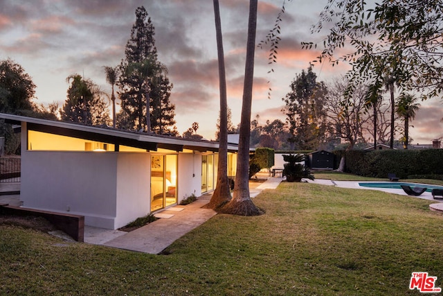 view of front facade with a yard, a fenced in pool, and a patio area