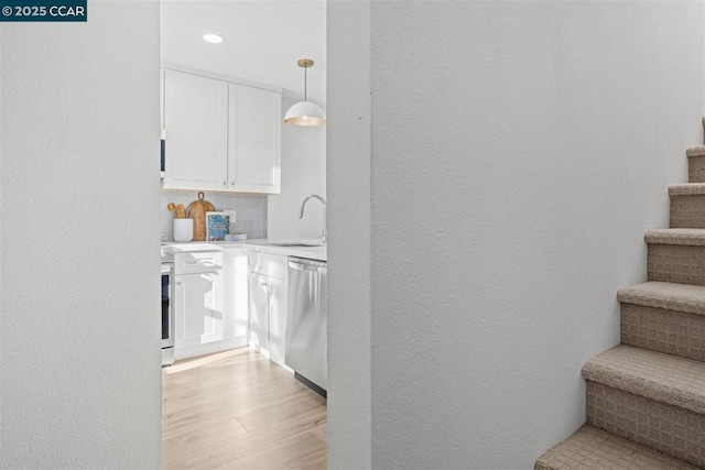 interior space with white cabinetry, decorative backsplash, decorative light fixtures, stainless steel dishwasher, and sink