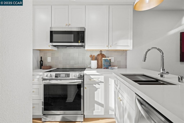 kitchen featuring appliances with stainless steel finishes, white cabinets, tasteful backsplash, and sink