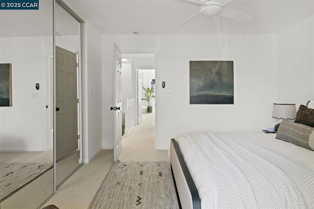 bedroom featuring ceiling fan, light carpet, and a closet