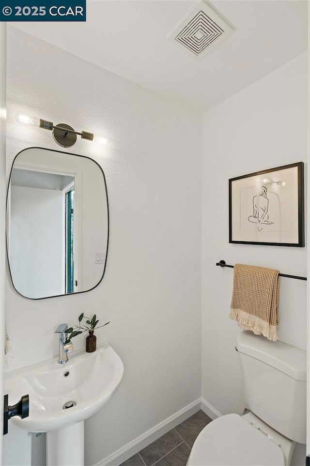 bathroom with toilet, tile patterned floors, and sink