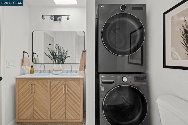 laundry room with sink, stacked washer / dryer, and a skylight