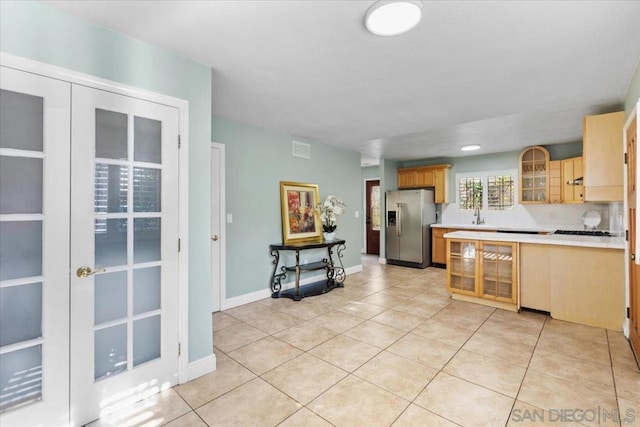 kitchen featuring stainless steel refrigerator with ice dispenser, light brown cabinets, decorative backsplash, and light tile patterned floors