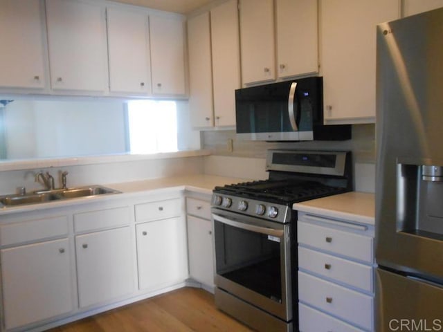 kitchen featuring appliances with stainless steel finishes, white cabinetry, and sink