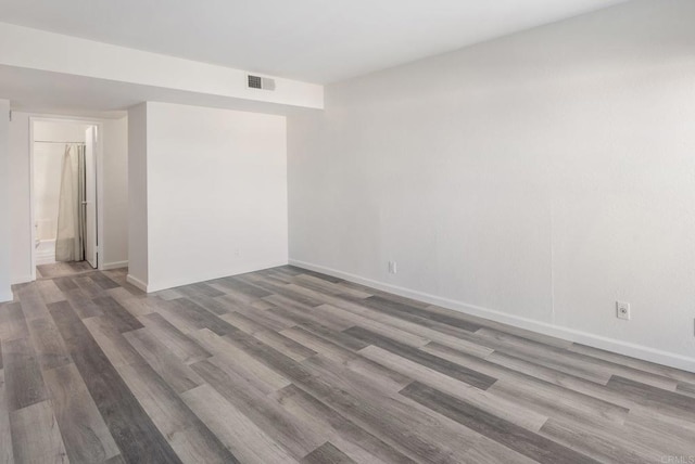 unfurnished room with baseboards, visible vents, and wood finished floors