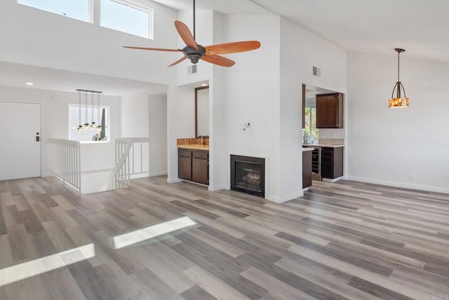 unfurnished living room with light wood-style floors, a healthy amount of sunlight, visible vents, and baseboards