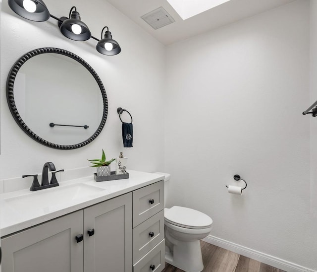 bathroom featuring toilet, wood finished floors, visible vents, vanity, and baseboards