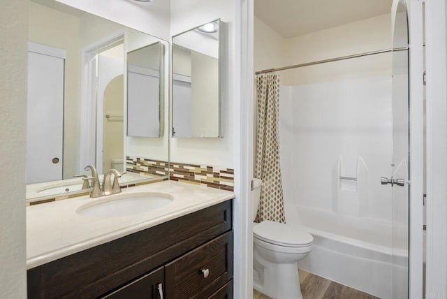 bathroom featuring toilet, wood finished floors, vanity, tasteful backsplash, and shower / bathtub combination with curtain