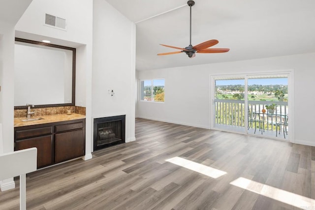 bar featuring visible vents, light wood-style floors, a fireplace, high vaulted ceiling, and a sink