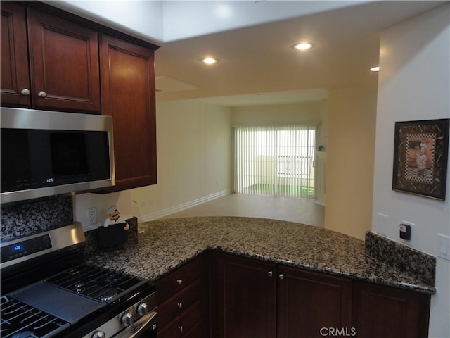 kitchen featuring dark stone counters, kitchen peninsula, and appliances with stainless steel finishes