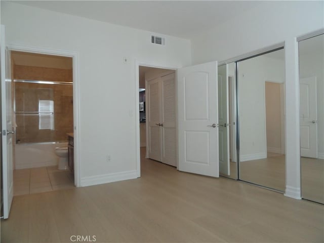 unfurnished bedroom with light wood-type flooring and ensuite bath