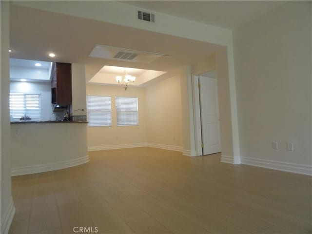 unfurnished living room featuring a notable chandelier and a tray ceiling