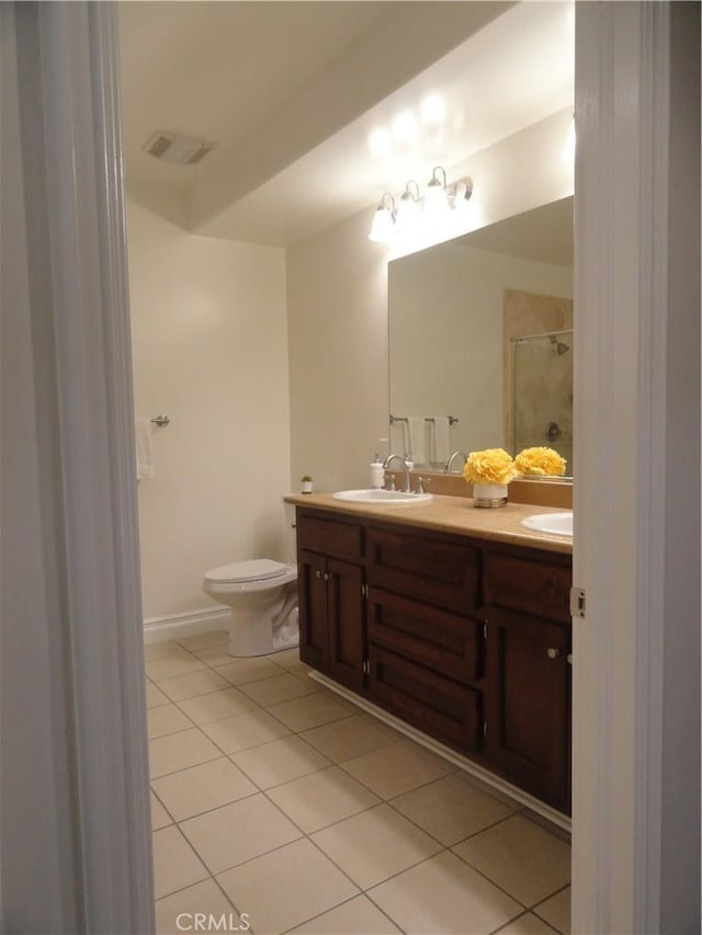 bathroom with a shower with shower door, toilet, vanity, and tile patterned flooring