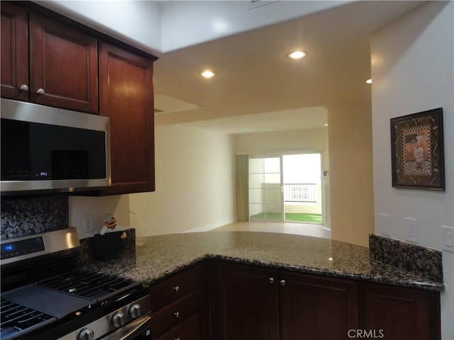 kitchen with dark stone countertops, kitchen peninsula, and appliances with stainless steel finishes