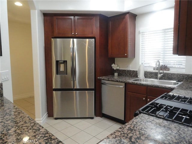 kitchen featuring sink, stainless steel appliances, dark stone counters, and light tile patterned flooring