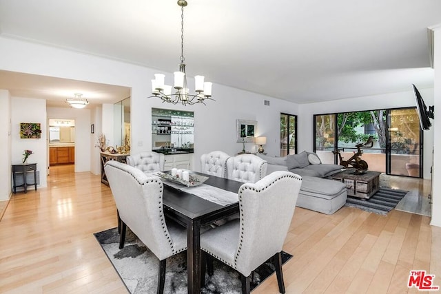 dining room featuring light wood-type flooring and a chandelier