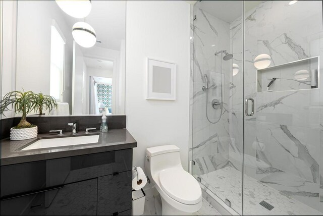 bathroom with walk in shower, vanity, and toilet