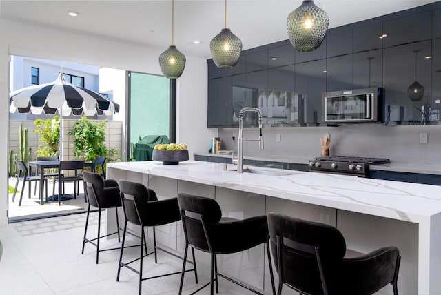 kitchen featuring decorative light fixtures, a kitchen bar, appliances with stainless steel finishes, and sink