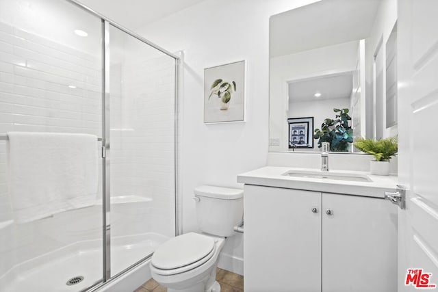 bathroom featuring toilet, a shower with shower door, and vanity