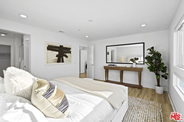 bedroom with a walk in closet and light hardwood / wood-style flooring