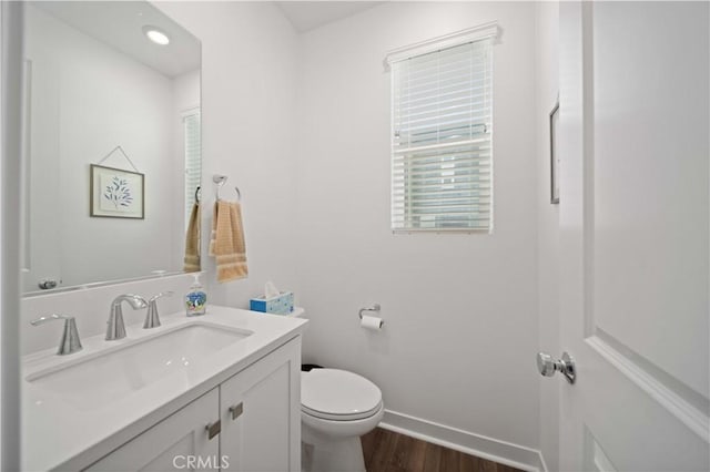 bathroom with toilet, hardwood / wood-style floors, and vanity