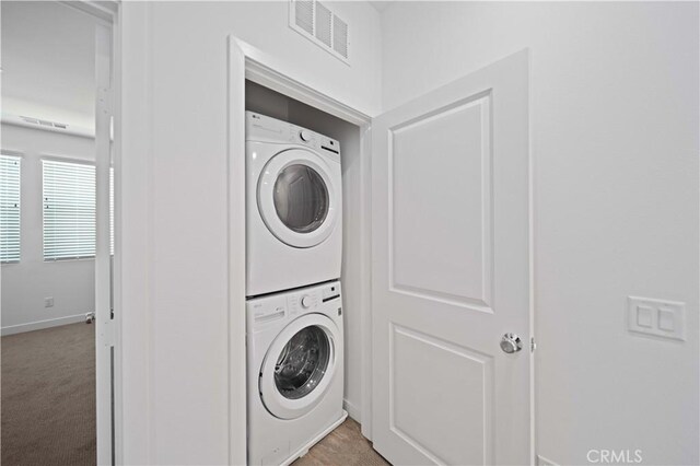 27014 Hummingbird Ln, Valencia, CA 91381 - laundry area featuring visible vents, stacked washer / dryer, baseboards, laundry area, and light carpet
