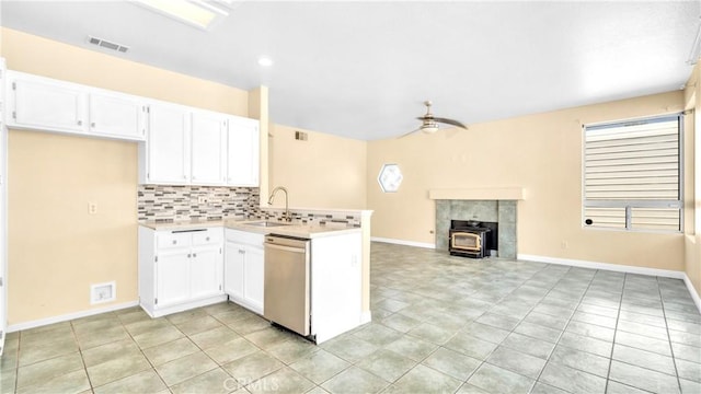 kitchen featuring sink, white cabinetry, dishwasher, a wood stove, and ceiling fan